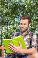 Handsome hipster reading in the park