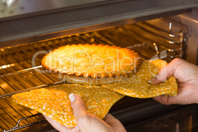 Woman taking fresh pie out of oven