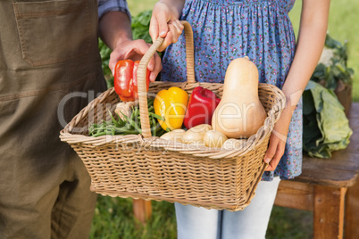 Couple holding basket of vegetables