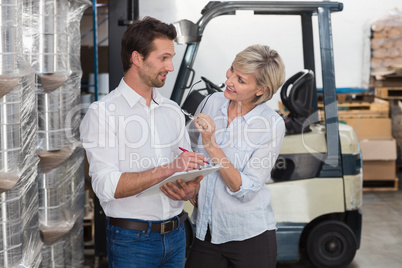 Smiling warehouse managers working on clipboard