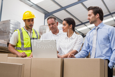 Warehouse managers and worker looking at laptop