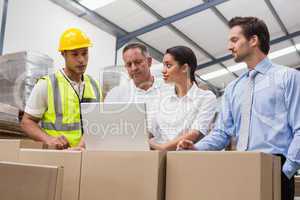 Warehouse managers and worker looking at laptop