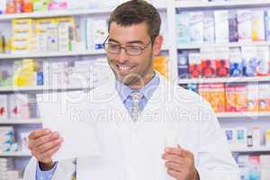 Happy pharmacist looking at prescription
