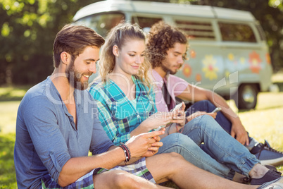 Hipsters sitting on the grass texting