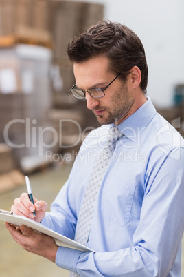 Portrait of focused manager writing on his clipboard