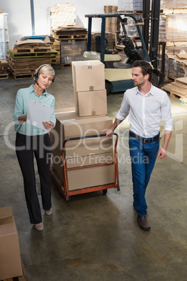 Manager walking with her colleague pulling trolleys