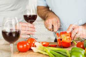 Mature couple having red wine while making dinner