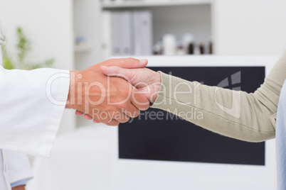 Male doctor and female patient shaking hands