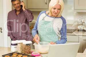 Happy blonde preparing dough with husband behind