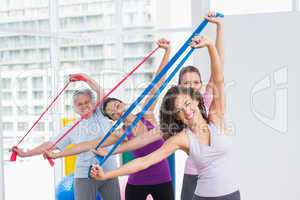 Happy female friends exercising with resistance bands