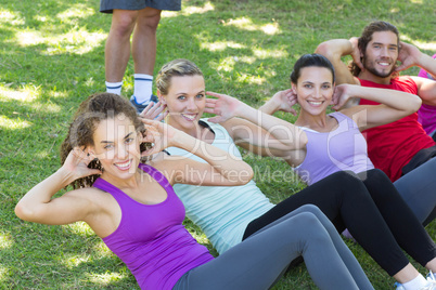 Fitness group doing sit ups in park with coach