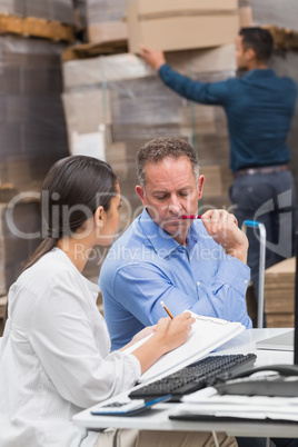 Warehouse manager writing on clipboard