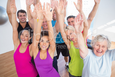 Cheerful friends with hands raised at fitness studio