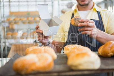 Worker in apron holding box and bread