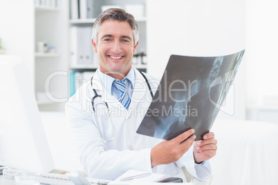 Happy doctor holding x-ray in clinic