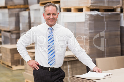 Smiling boss leaning on stack of cartons