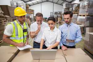 Warehouse managers and worker looking at laptop