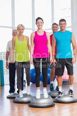 People standing on balance balls in gym