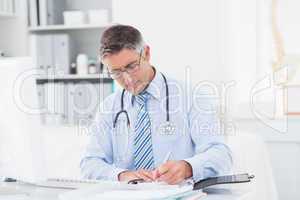 Male doctor writing on paper at table