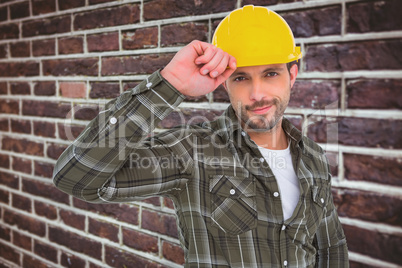 Composite image of smiling handyman holding helmet