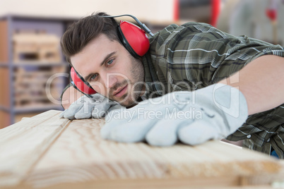 Composite image of carpenter measuring wooden plank