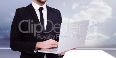 Composite image of mid section of a businessman using laptop