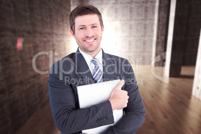 Composite image of businessman holding his laptop tightly