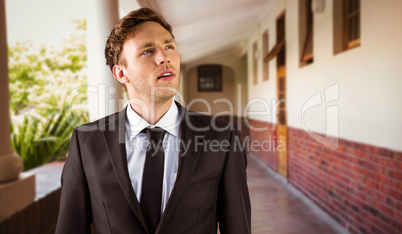 Composite image of young businessman thinking and looking up