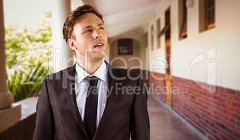 Composite image of young businessman thinking and looking up