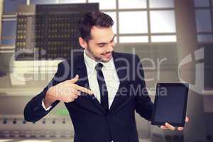 Composite image of happy businessman pointing with his tablet