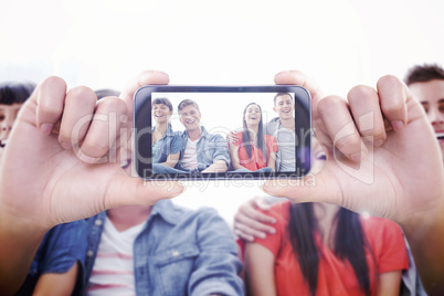 Composite image of hand holding smartphone showing