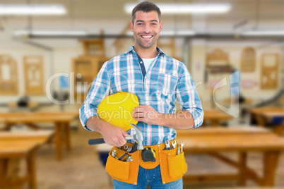 Composite image of smiling handyman holding hardhat and hammer