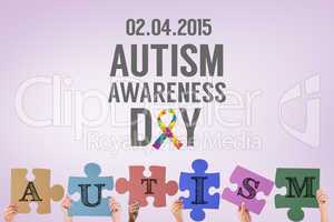 Composite image of hands holding up autism jigsaw pieces