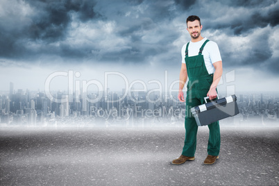 Composite image of repairman holding toolbox