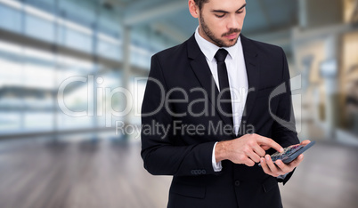 Composite image of concentrated businessman in suit using calcul