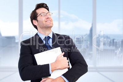 Composite image of handsome businessman holding his laptop