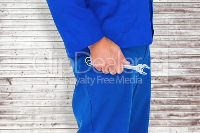 Composite image of mechanic holding spanners on white background