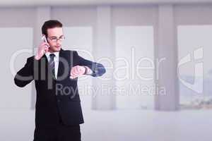 Composite image of serious businessman phoning while checking ti
