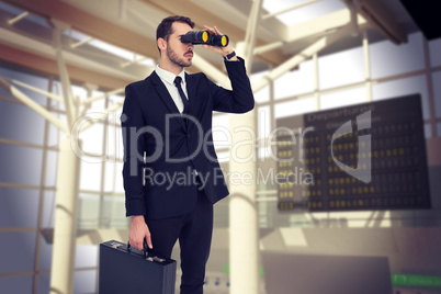 Composite image of businessman holding a briefcase while using b