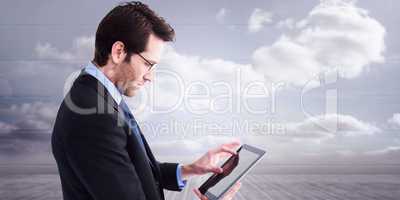 Composite image of businessman standing while using a tablet pc