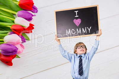 Composite image of cute pupil holding chalkboard