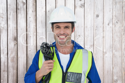 Composite image of confident electrician with wire against white