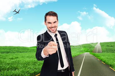 Composite image of happy businessman pointing at camera