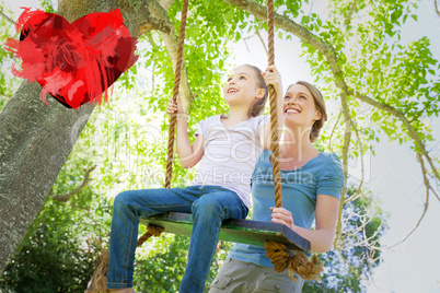 Composite image of happy mother swinging daughter at park