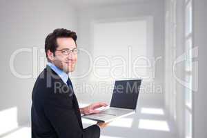 Composite image of smiling businessman using a laptop