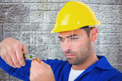 Composite image of electrician wearing hard hat while cutting wi