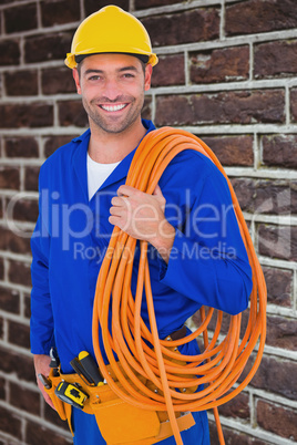 Composite image of smiling handyman with rolled wire on white ba