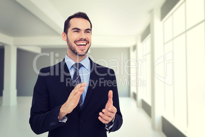 Composite image of happy businessman standing and clapping