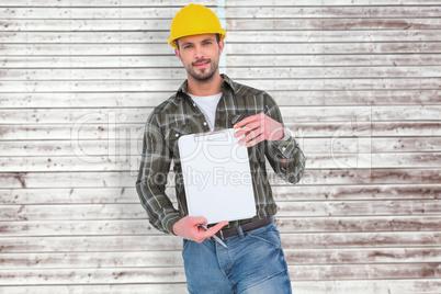 Composite image of smiling manual worker holding clipboard