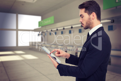 Composite image of concentrated businessman touching his tablet